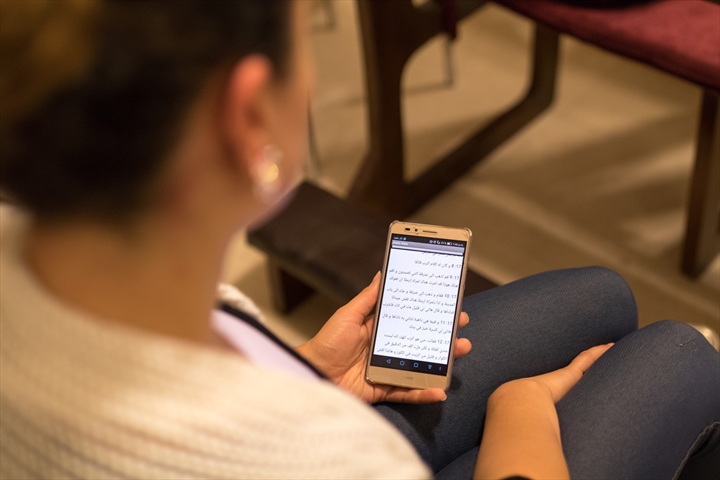 Young woman reading the Bible on her smartphone