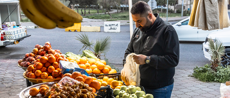 A man buys fruit at a market stall in Iraq