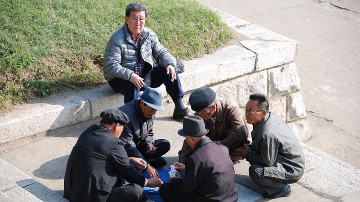   Old men sitting together on stairs playing cards