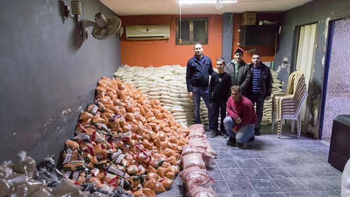 Volunteers stood next to bags of food in Syria.