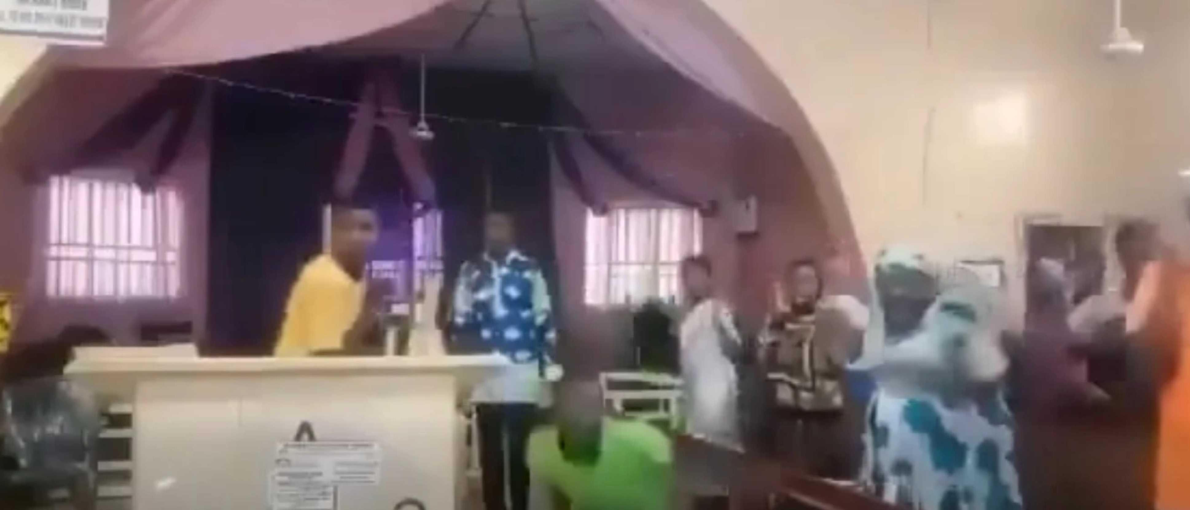 A church congregation reacts to the sound of gunfire, ducking.