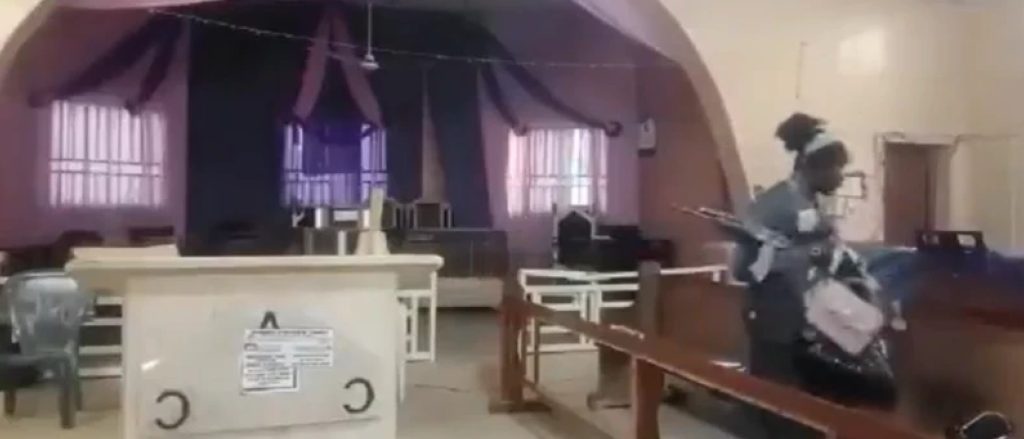 A man with a gun takes bags from church pews