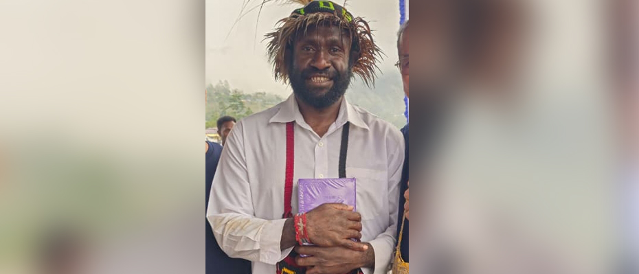 Man from Indonesia smiles at the camera holding a Bible