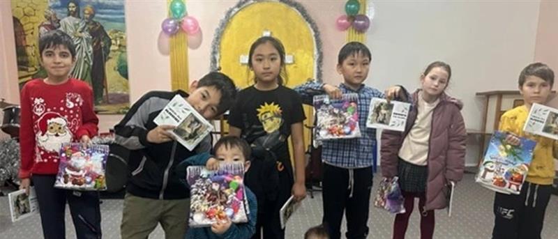 Children holding cards and gifts stood in a line
