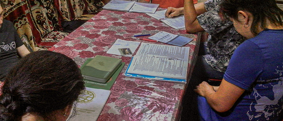 People gathered around a patterned table with books on it