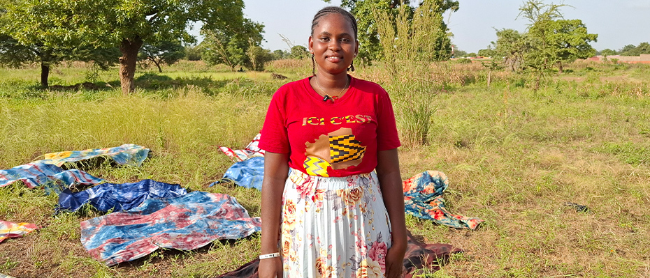 Burkinabe woman smiles wearing a red t-shirt in a field