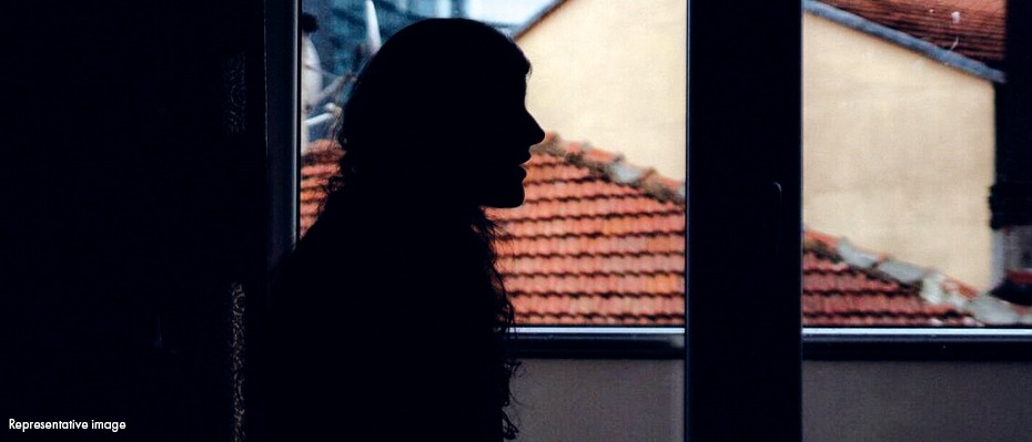 A woman in shadows stands in front of a window