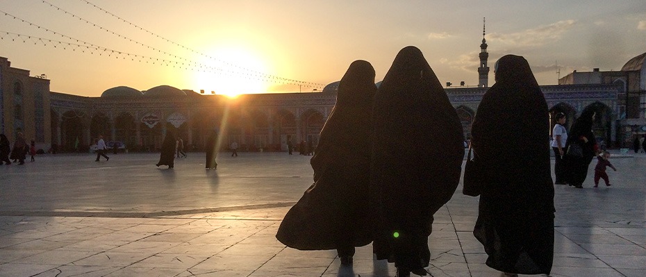 Women walk towards a sunset on a city street