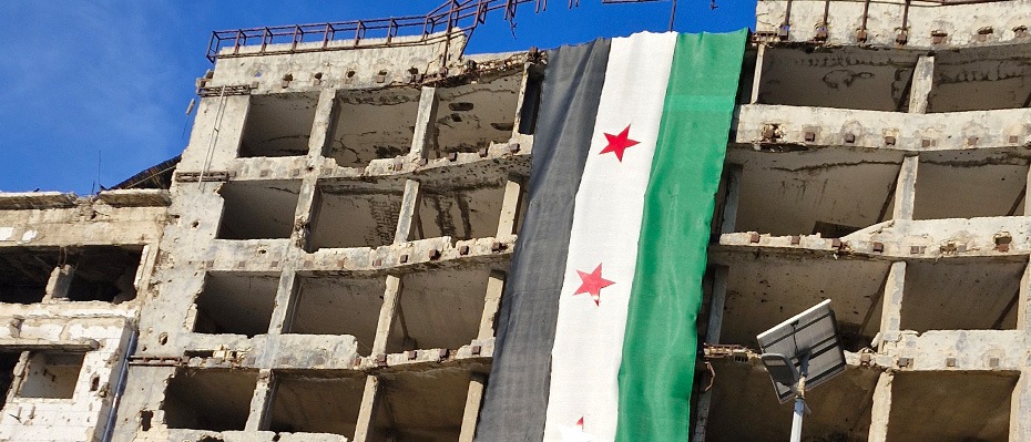 The Syrian flag hangs off a dilapidated building