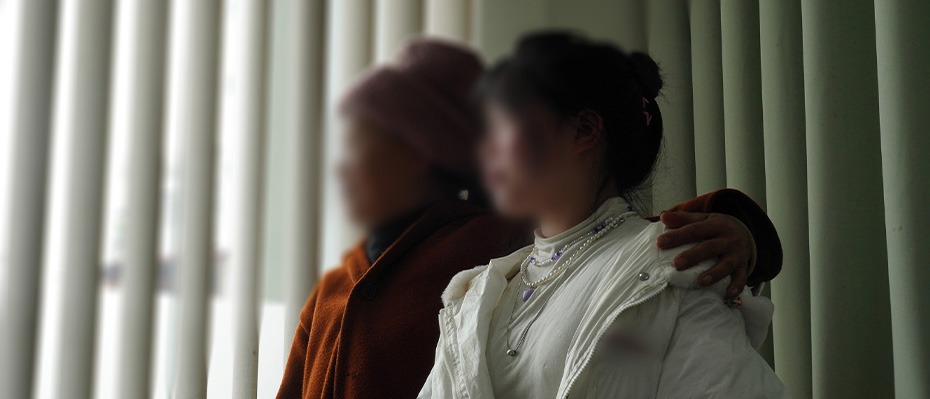 Two women look out of a window