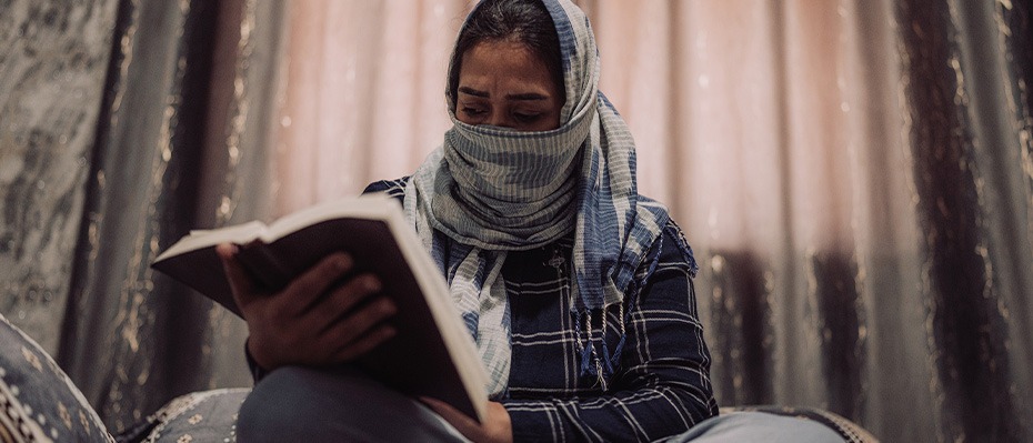 Woman wearing a headscarf reads a Bible
