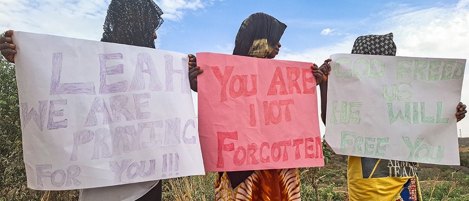 Three African girls hold up homemade signs