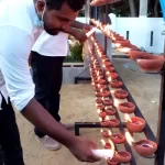 Man lights a candle and places it on a candle stand