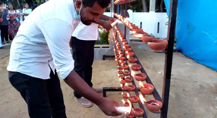 Man lights a candle and places it on a candle stand