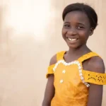 Aicha from Burkina Faso smiles, wearing a yellow dress