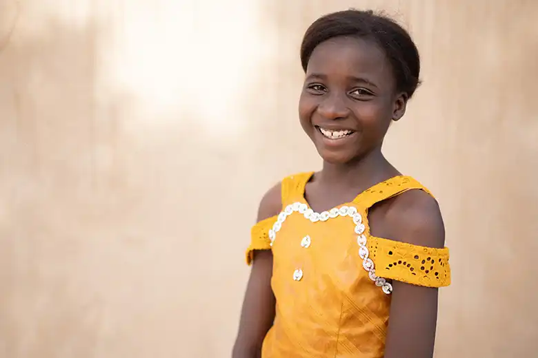 Aicha from Burkina Faso smiles, wearing a yellow dress