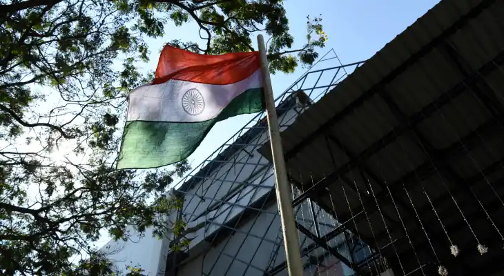 The Indian flag on a pole billows in the wind.
