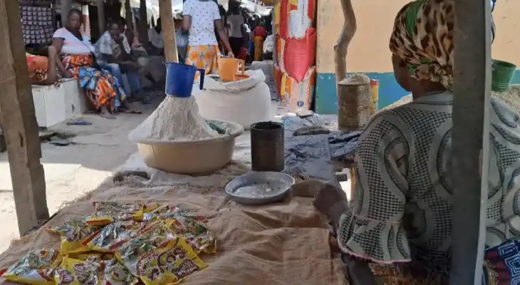 Ana from Mozambique sits at her marketplace stall with items she is selling on it.