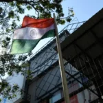The Indian flag on a pole billows in the wind.
