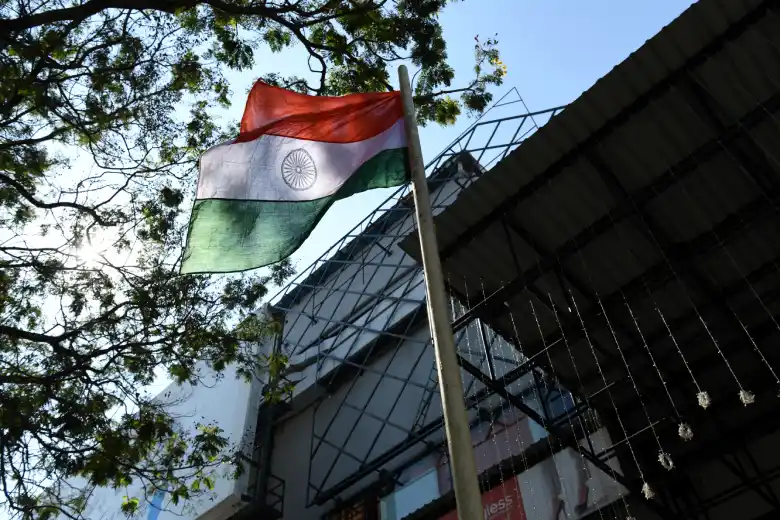 The Indian flag on a pole billows in the wind.