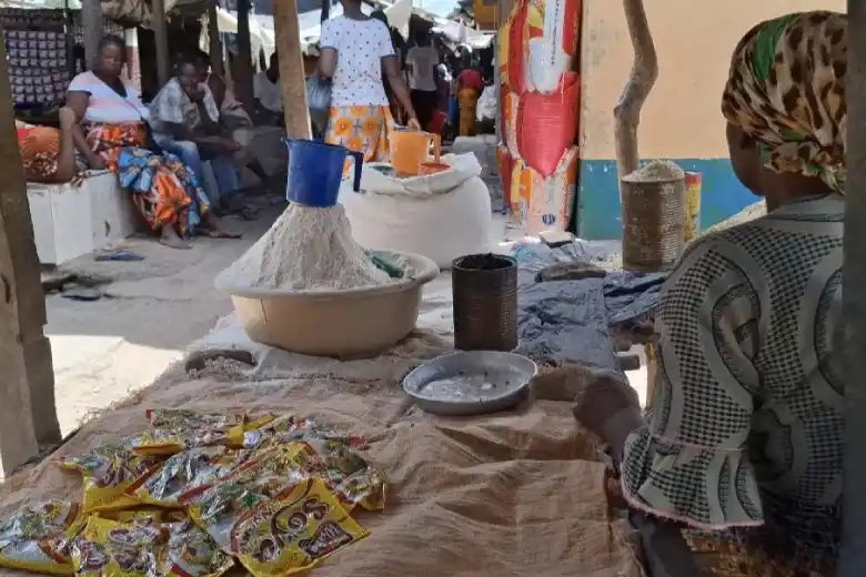Ana from Mozambique sits at her marketplace stall with items she is selling on it.